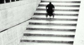 En person i rullstol p vg upp fr en trappa.