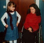 En flicka str bredvid en kvinna i rullstol.
